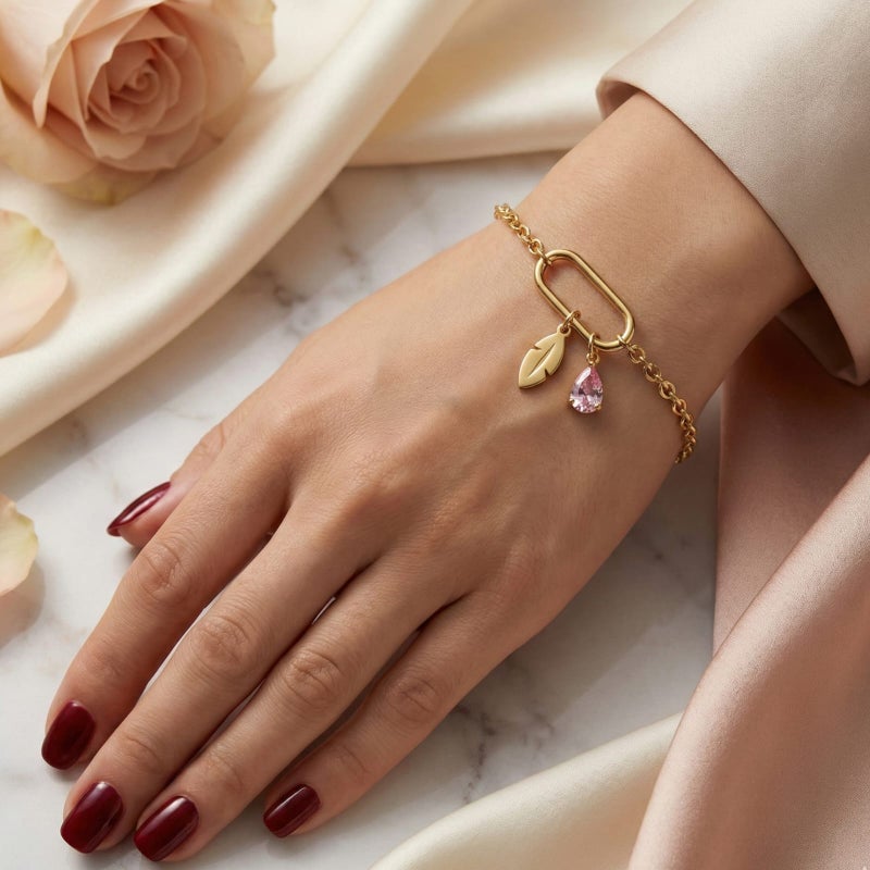 This attractive gold bracelet, crafted from rust-resistant stainless steel, features a modern link ring from which a delicate feather and a sparkling pink stone dangle. It has an adjustable clasp for a perfect fit. - Image 2